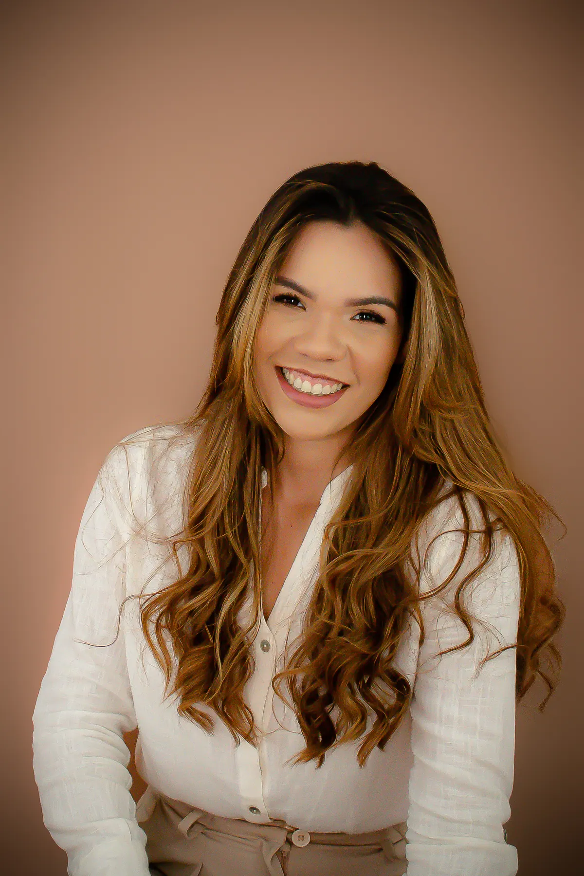 Retrato de Gabrielle Rocha, fotógrafa, sorrindo com blusa branca