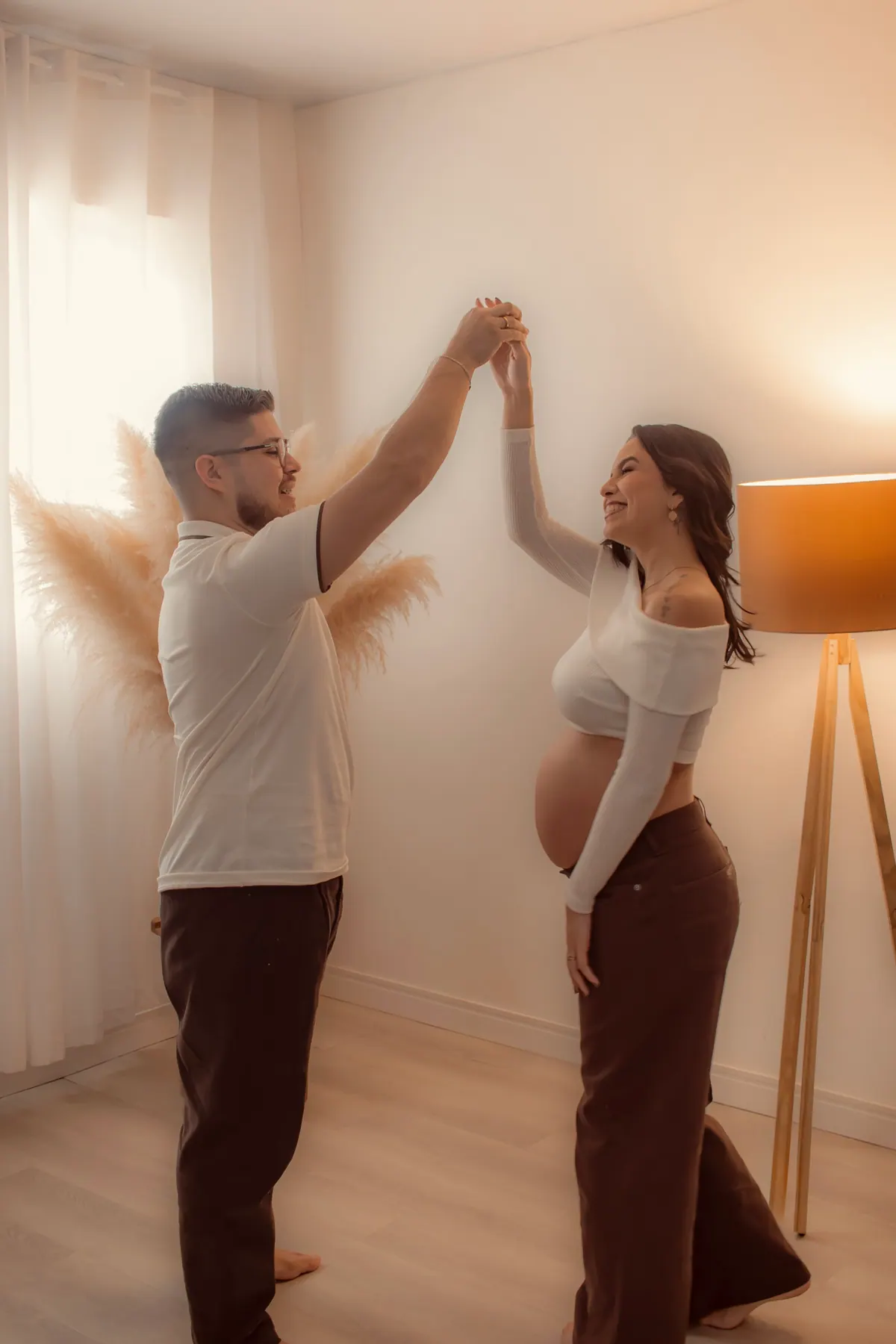 Casal dançando de mãos dadas no ensaio gestante